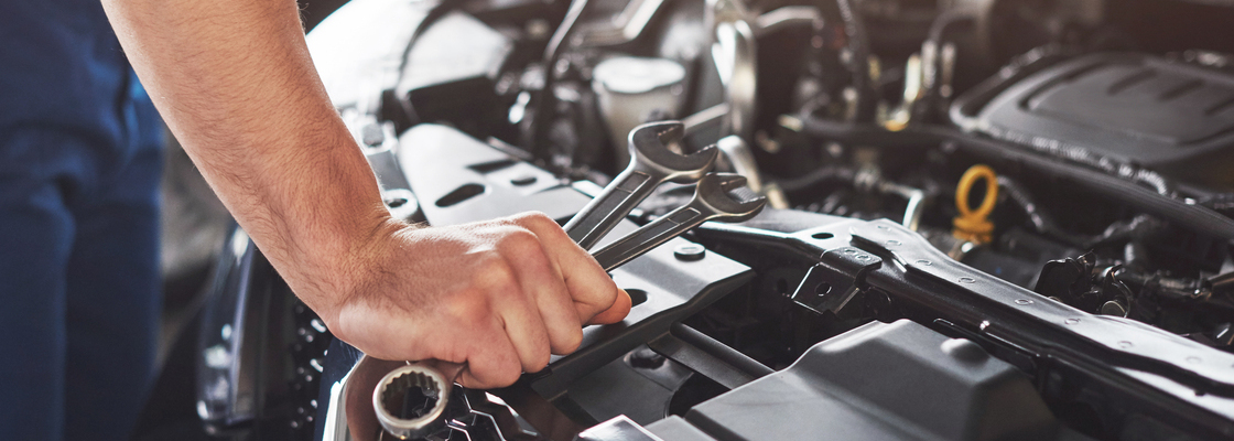 Picture showing muscular car service worker repairing vehicle.