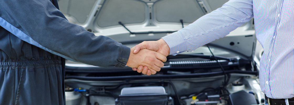 Car mechanic and customer shaking hands.